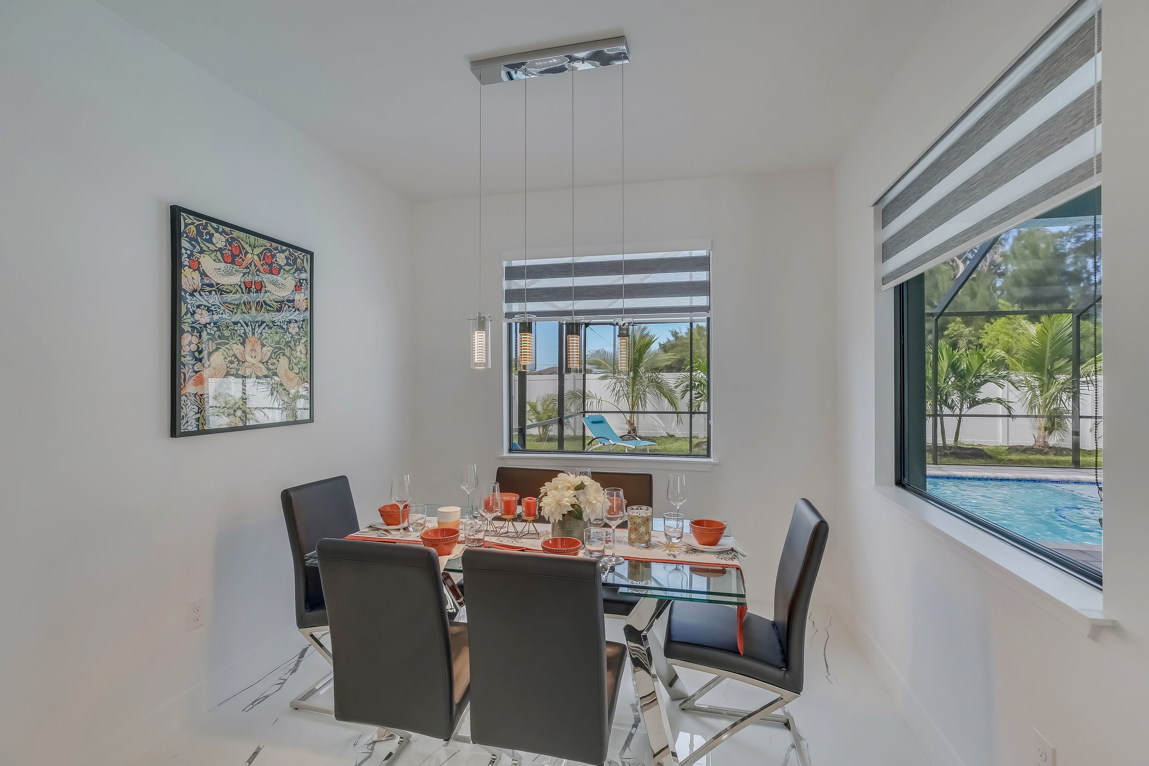 A dining area with a glass table, black chairs, and a view of a swimming pool through large windows.