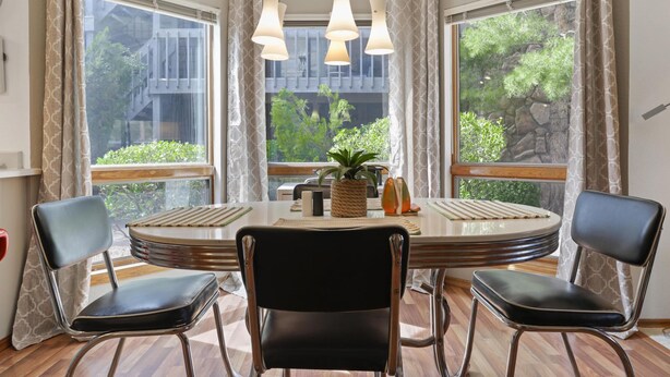 A dining area with a round table, black chairs, and a hanging light fixture. - Perfect Arizona Mountain Retreat (Payson)