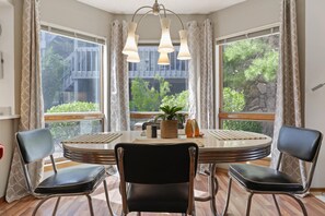Un comedor con una mesa redonda, sillas negras y una lámpara colgante.