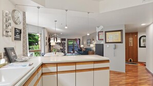 A modern kitchen with a central island, wooden cabinetry, pendant lighting, and a view into the living area. - Perfect Arizona Mountain Retreat (Payson)