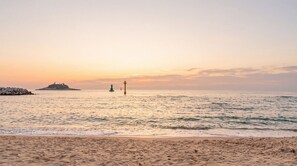 A beach with a sandy shore, calm sea, and a distant island with a lighthouse. - Sokcho World Pet-friendly Pension (Sokcho)