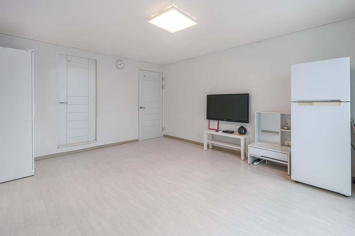 A spacious room with a flat-screen TV, a white cabinet, and a door.