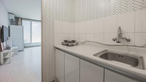 A modern kitchen with a herringbone tile backsplash, a stainless steel sink, and a gas stove. - Sokcho World Pet-friendly Pension (Sokcho)