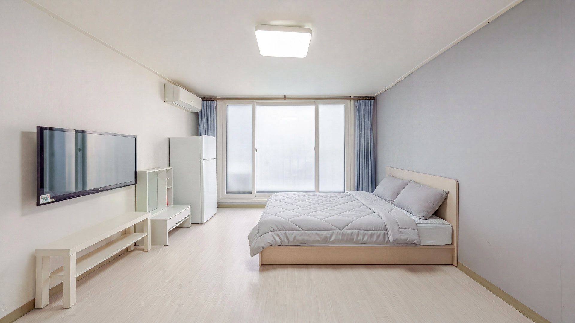 Une chambre moderne avec un lit, une télévision, une armoire et une fenêtre avec des rideaux.