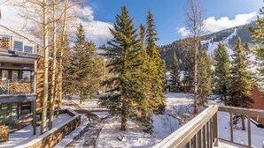 A snow-covered landscape with a stone building and a wooden deck. - Slopeside #2775 by Summit County Mountain Retreats (Keystone)
