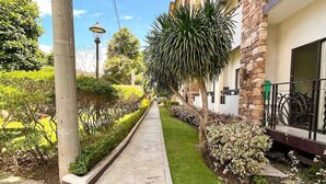 Un immeuble résidentiel doté d’un chemin piétonnier pavé, d’espaces verts et surplombant un ciel dégagé.