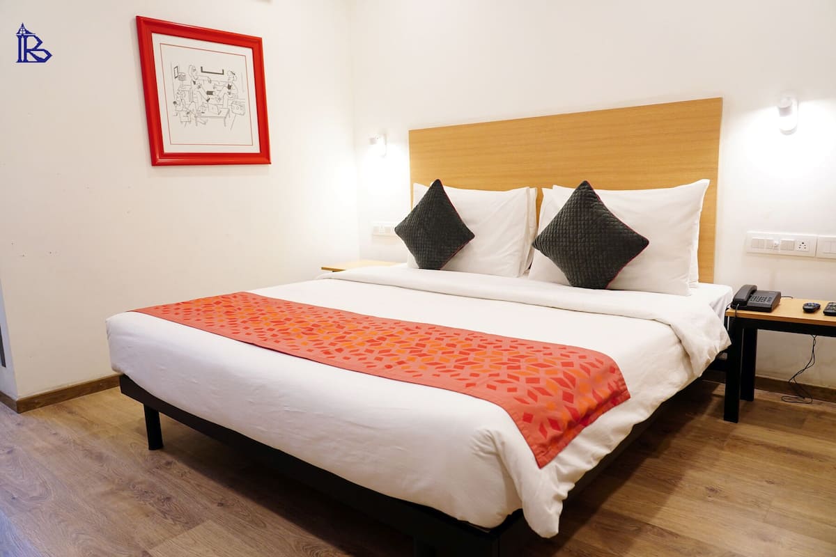 A neatly made bed with a patterned throw, a wooden headboard, and a framed picture on the wall.