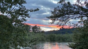 A river surrounded by dense foliage with a sunset in the background. - Exotic Waterfront Getaway (Salem)