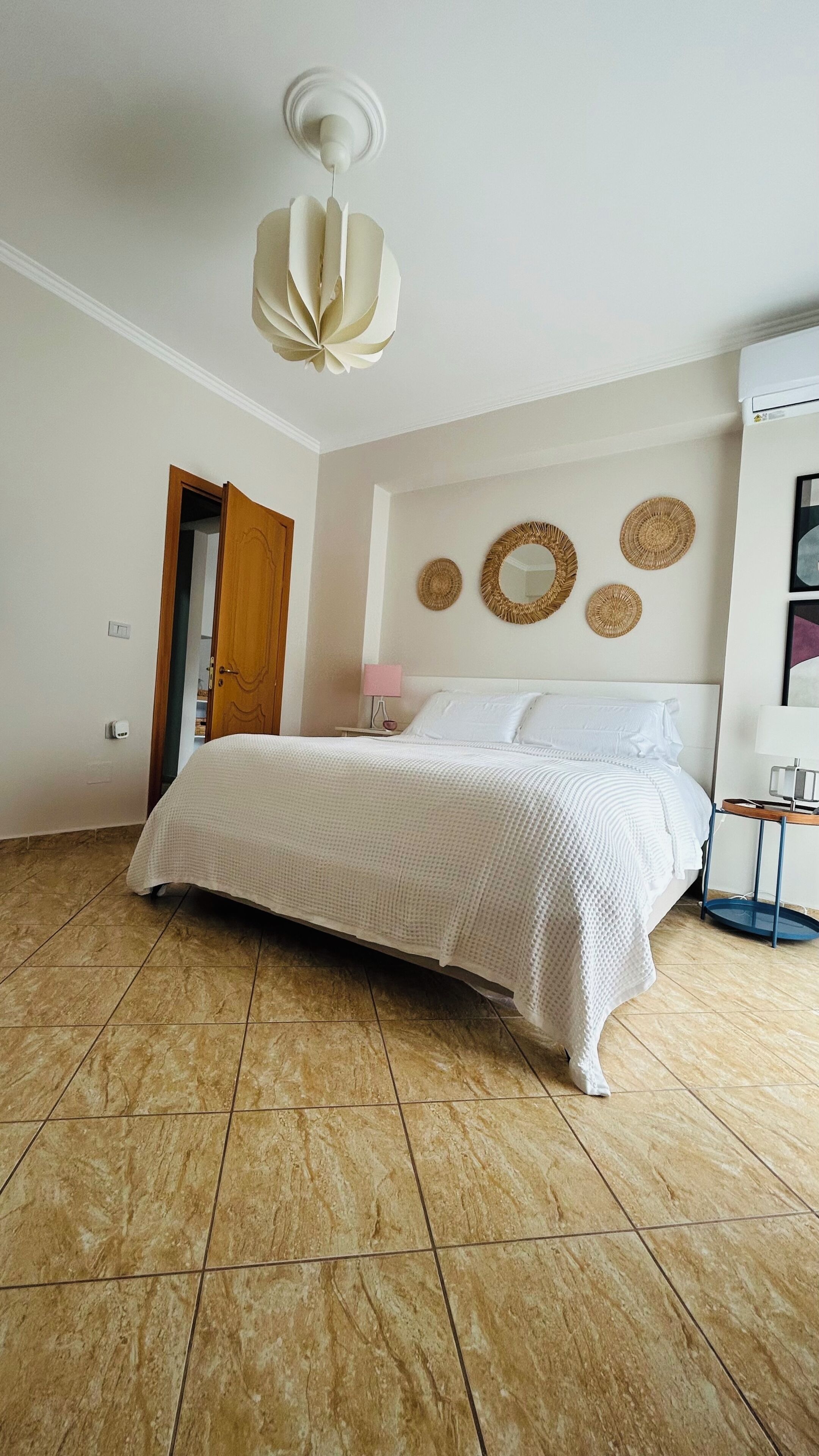 Une chambre à coucher comprenant un lit, une porte, un climatiseur fixé au mur et un ventilateur de plafond.