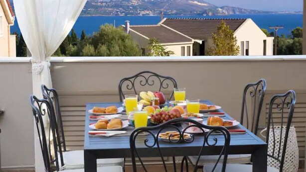Ein Balkon mit Frühstückstisch, mit Blick auf die Küste.
