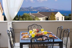 A balcony with a table set for breakfast, overlooking a coastal view. - Bright suite (Ληξούρι)