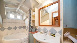 Ein Badezimmer mit einer Badewanne, einem Waschbecken mit Spiegel und einer Duschkabine.