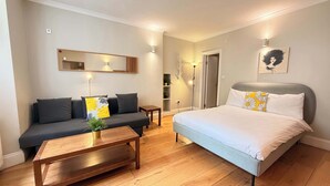 Ein modernes Hotelzimmer mit einem Bett, einem Sofa und einem kleinen Tisch mit einer Pflanze.