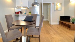 Une cuisine moderne avec des armoires blanches, une hotte de cuisinière en acier inoxydable et un ordinateur portable posé sur la table à manger.