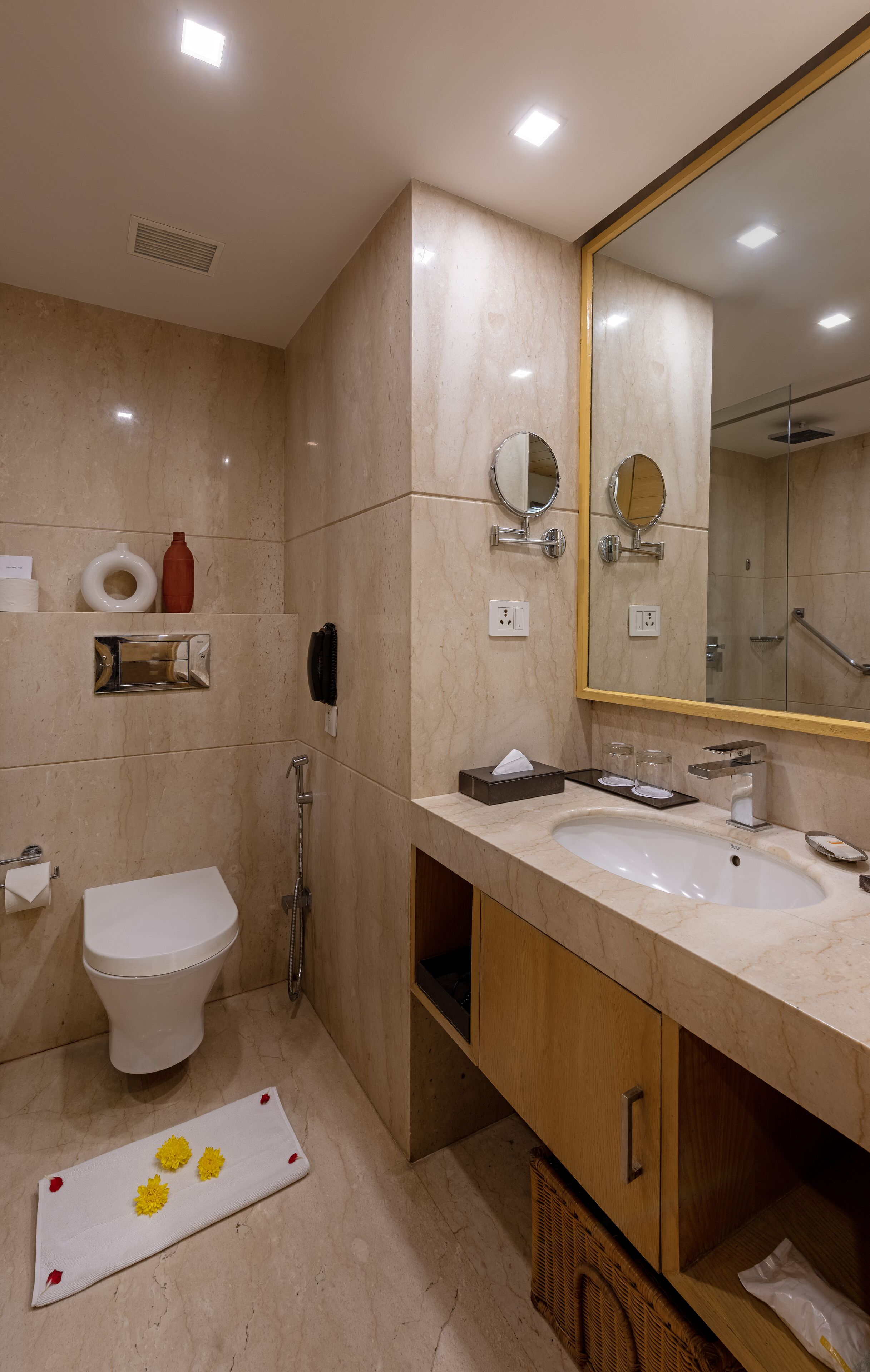 Un baño moderno con un espejo grande, dos lavamanos, un inodoro y una ducha.