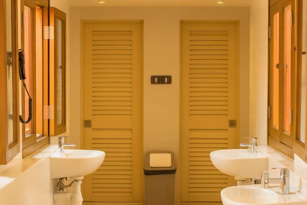 A bathroom with two sinks, a mirror, and a trash bin.