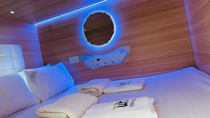 Habitación de hotel moderna con pared de madera, lámpara circular, panel de control y camas ordenadas con toallas.