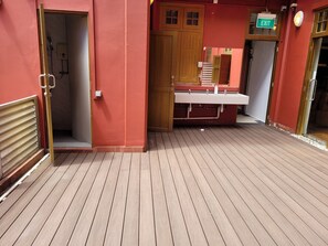 Un pasillo con piso de madera, un baño con ducha y una señal de salida.