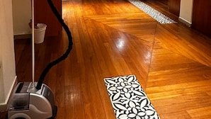 Habitación de hotel con suelo de madera, un aspirador, un alfombra estampado y un mostrador de recepción.