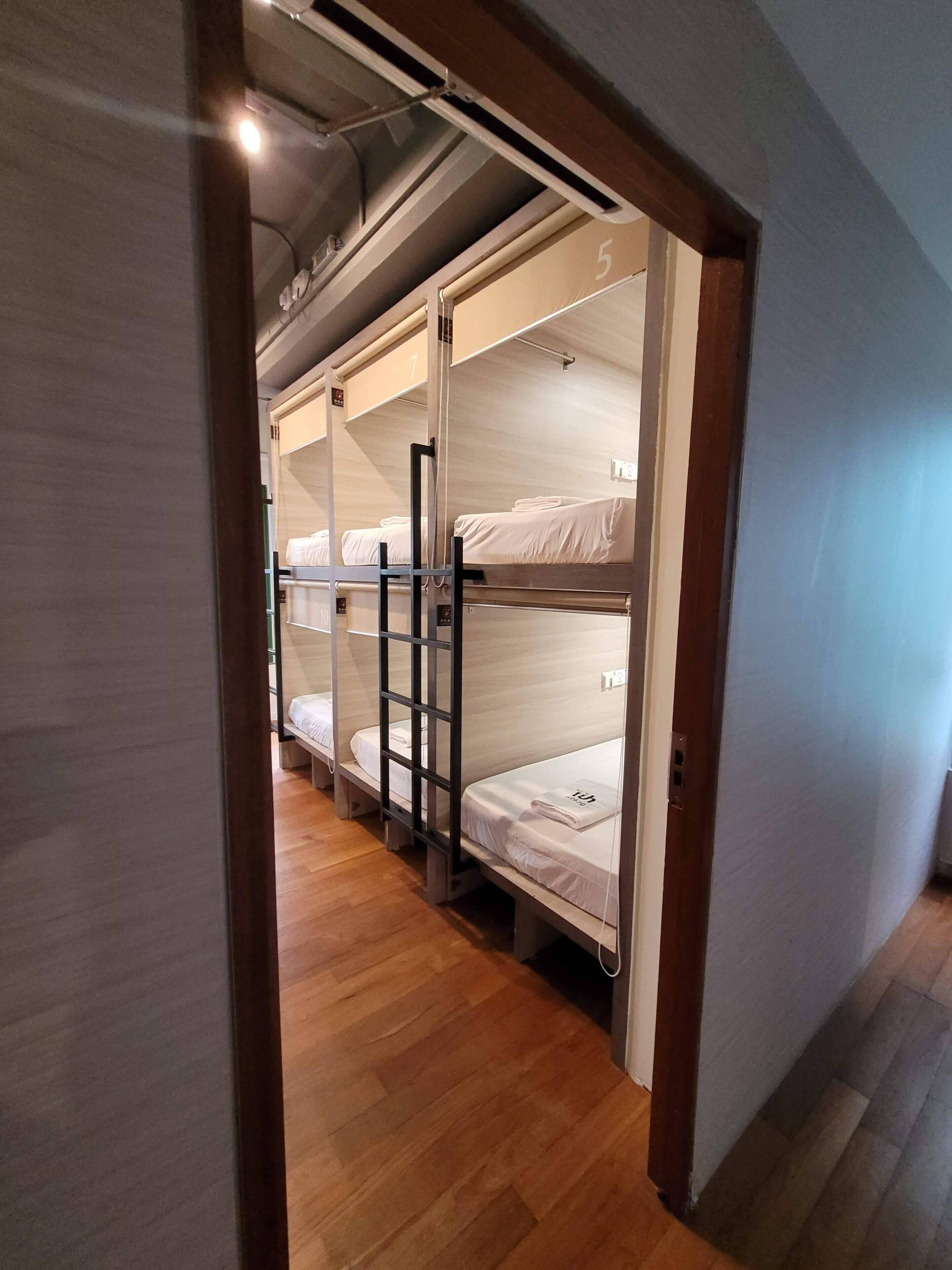 Pasillo que conduce a un dormitorio con literas, suelo de madera y el número 5 visible en la pared.