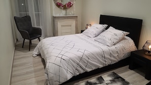 A bedroom with a bed, a chair, a mirror, and a fireplace. - Luxurious apartment, wifi, air conditioning, 50M from the beach (Nice)