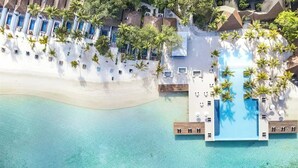 An aerial view of a resort with a beach, a pool area, and palm trees.