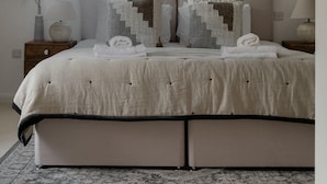 A bedroom with a large bed, two pillows, a bedside table, a lamp, and a painting on the wall. - Design-Led- 2xSuper-King Beds- Ensuites- W Parking  (Eton)