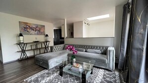 A modern living room with a grey sofa, a glass coffee table, and a painting on the wall. - Remodel Spacious Modern Retreat (Shoreline)