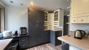 A kitchen with dark cabinets, a microwave, a coffee maker, and a kettle on the countertop. - Remodel Spacious Modern Retreat (Shoreline)