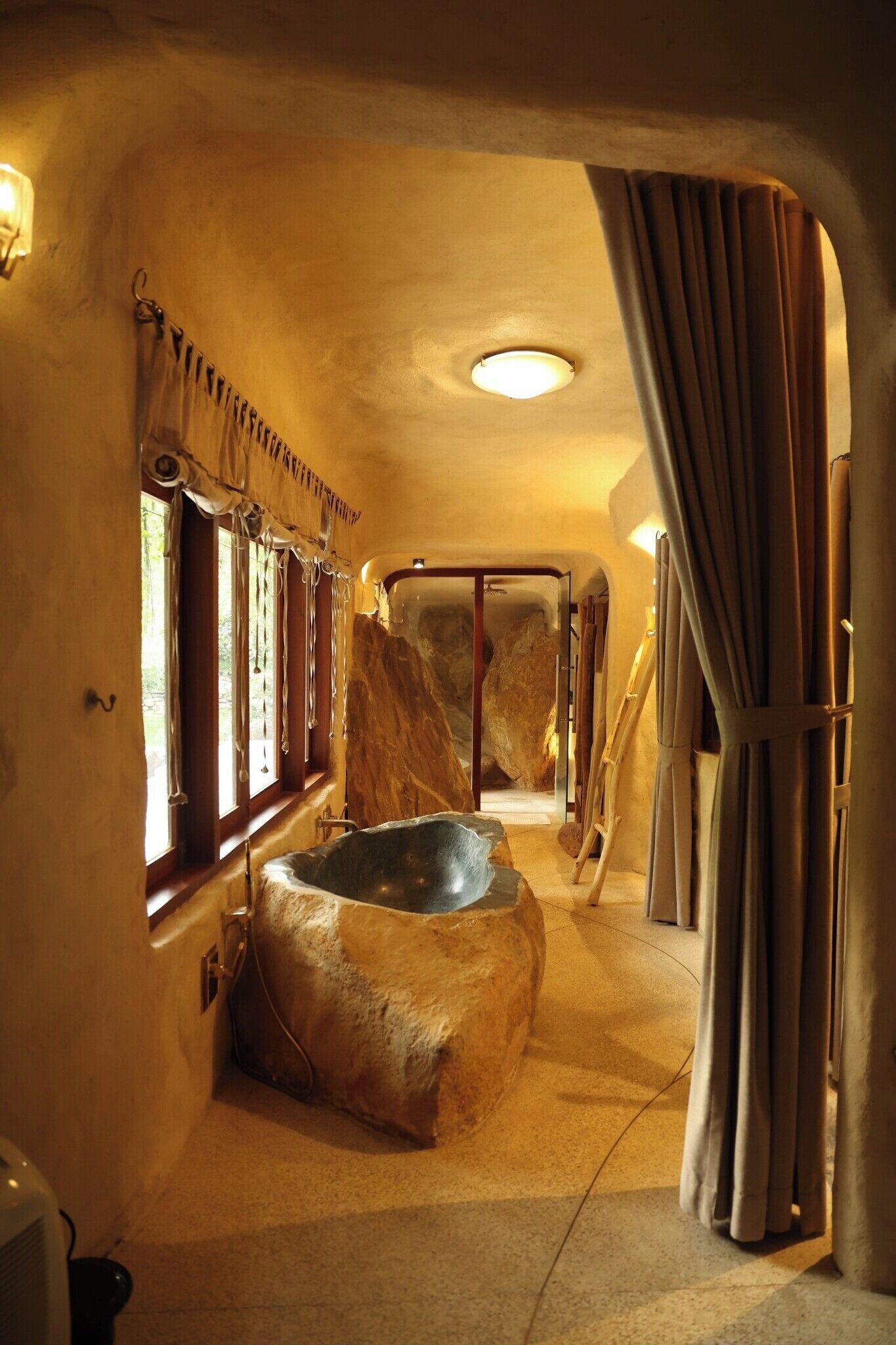 Un baño con una bañera grande, una ventana con cortinas y un perchero para toallas.