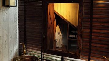 A rustic bathroom with wooden walls, a large mirror, and a wooden vanity with two basins.