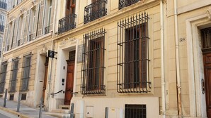 A building with multiple windows, some with metal bars, and a wooden door. - Maison Juste (Marseille)