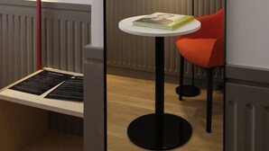 A modern room with a red-framed mirror, a small round table with a book, a red chair, and a black floor lamp. - Maison Juste (Marseille)