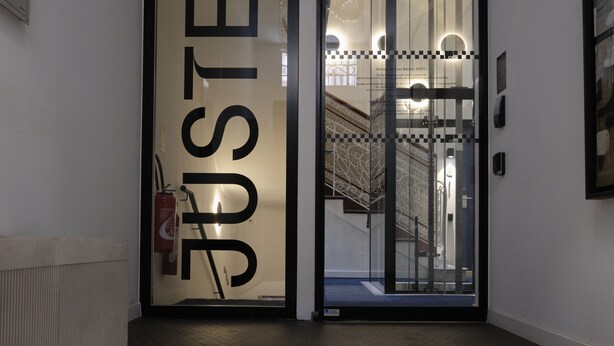 A hotel entrance with a glass door displaying the word "JUSTE" and a staircase leading to an upper floor. - Maison Juste (Marseille)