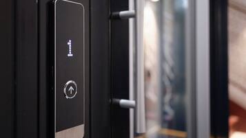 A close-up of a modern elevator control panel with a digital display and a directional arrow button.