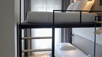 A bunk bed room with a window, curtains, and a small table.