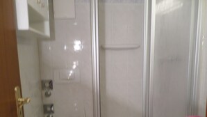 A bathroom with a toilet, a sink, and a shower enclosure.