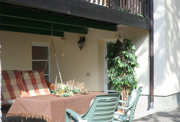 Un comedor con una mesa dispuesta para dos, una planta colgante y un sofá a cuadros.