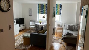 Un espacio habitable compacto con kitchenette, comedor, sofá y cama.