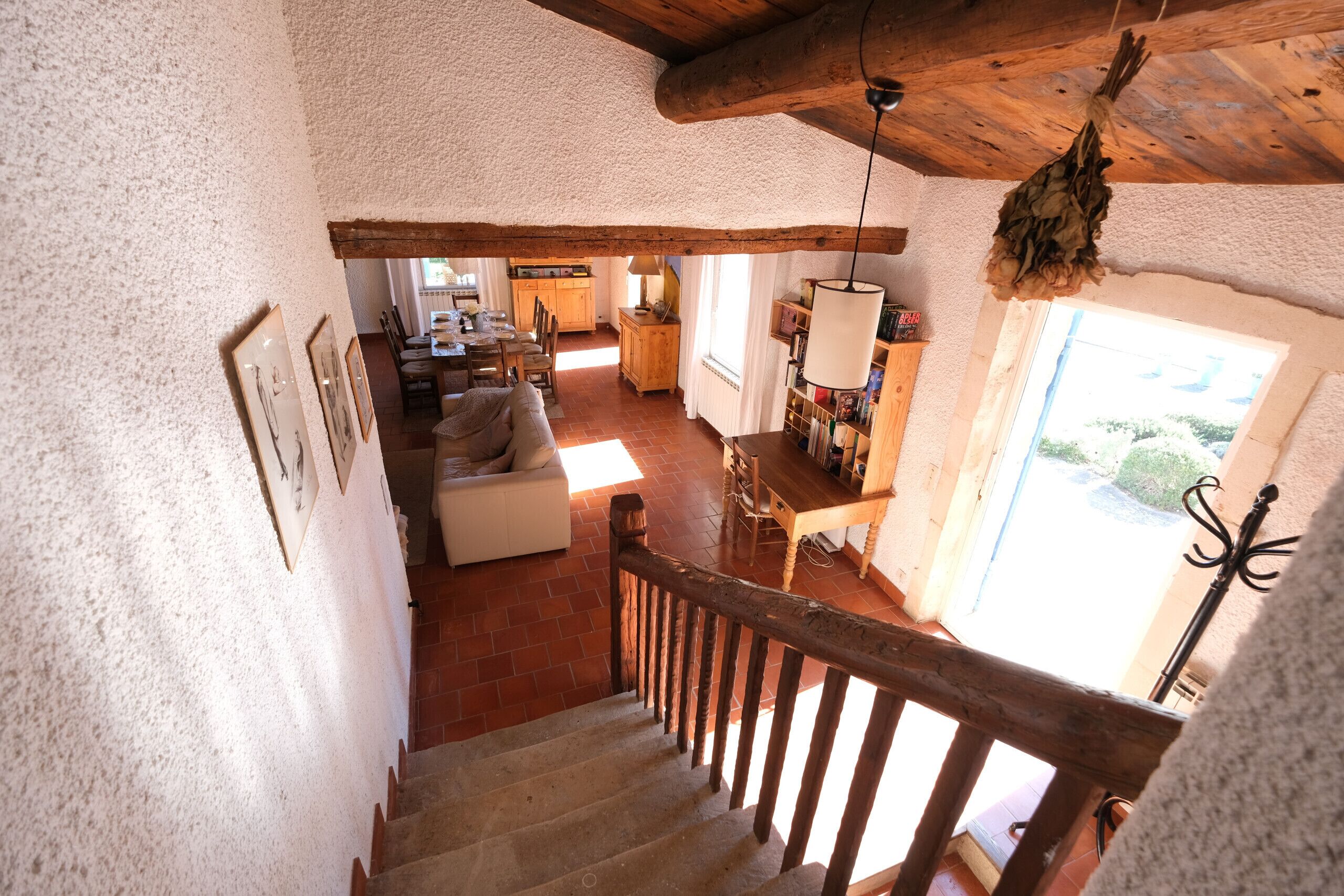 A rustic interior with a wooden staircase, a dining area, and a kitchen.