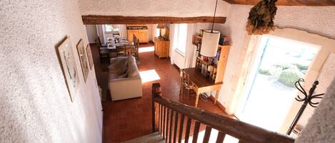 A rustic interior with a wooden staircase, a dining area, and a kitchen.