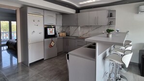 Eine moderne Küche mit grauen Schränken, einem eingebauten Backofen und einer großen Kochinsel mit Barhocker.