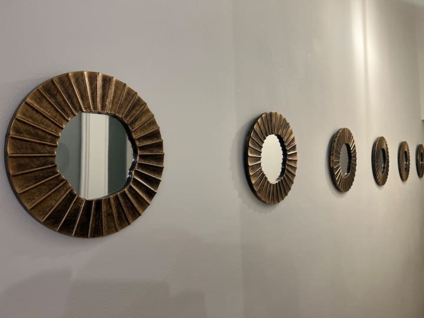 A wall with a large circular mirror and four smaller mirrors.
