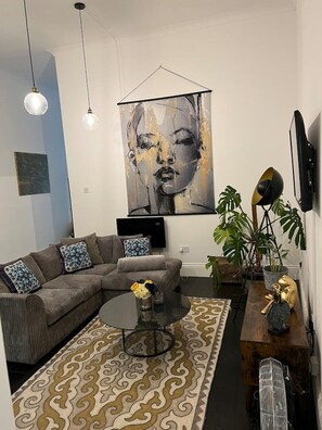 Ein modernes Wohnzimmer mit einem Ecksofa, einem Couchtisch, einem gemusterten Teppich und einem großen abstrakten Gemälde an der Wand.
