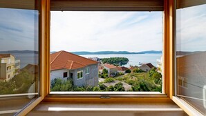 Una habitación con un ventanal que ofrece vistas a un pueblo costero y al mar.