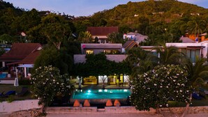 Ein Resort mit Swimmingpool, mehreren Gebäuden und einer hügeligen Landschaft im Hintergrund.