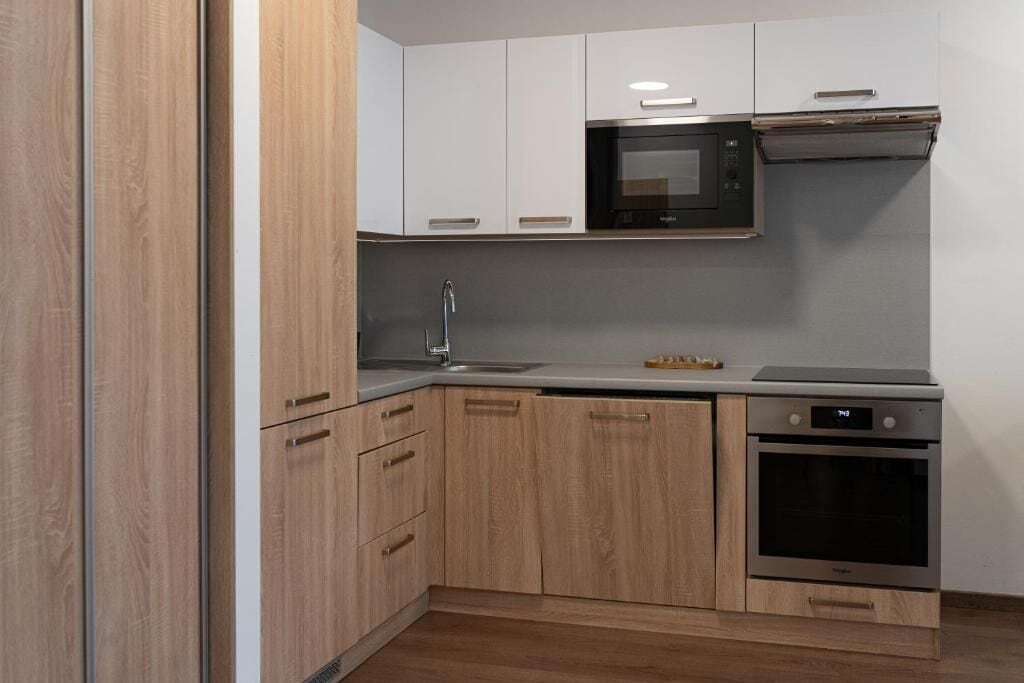 A modern kitchen with wooden cabinets, a stainless steel microwave, a built-in oven, and a sink.