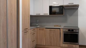 A modern kitchen with wooden cabinets, a stainless steel microwave, a built-in oven, and a sink.