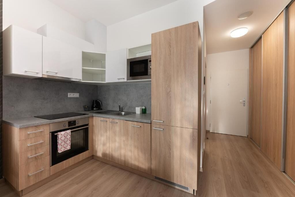 Una cocina moderna con armarios de madera, horno empotrado y microondas.