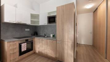 Eine moderne Küche mit Holzschränken, einem eingebauten Backofen und einer Mikrowelle.